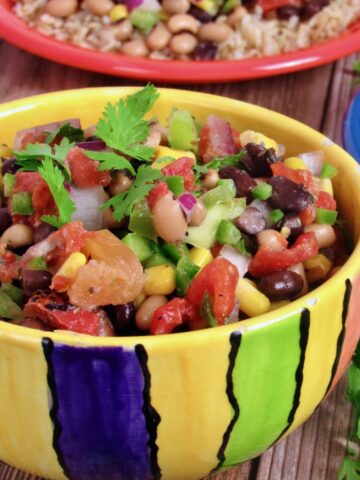 Bowl of cowboy caviar, featuring a mix of black beans, corn, tomatoes, and peppers, ready to serve with chips.