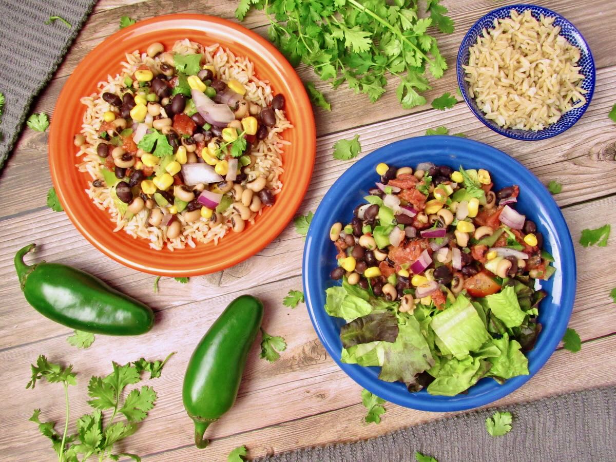 Cowboy Caviar, served with rice and fresh lettuce, with cilantro and jalapenos scattered around the plates.