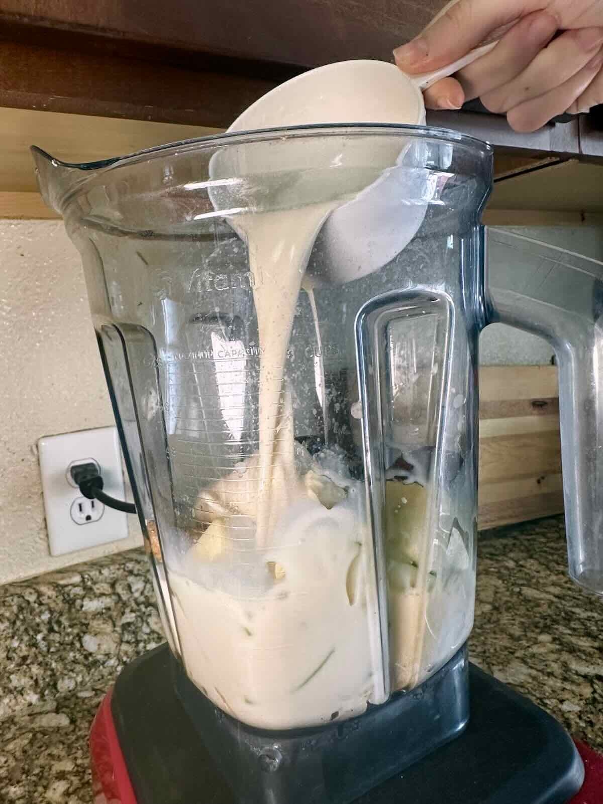 Pouring soy milk into a blender for a dairy-free smoothie.