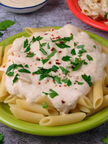 Vegan Alfredo Pasta Sauce, served on penne pasta with fresh herbs.