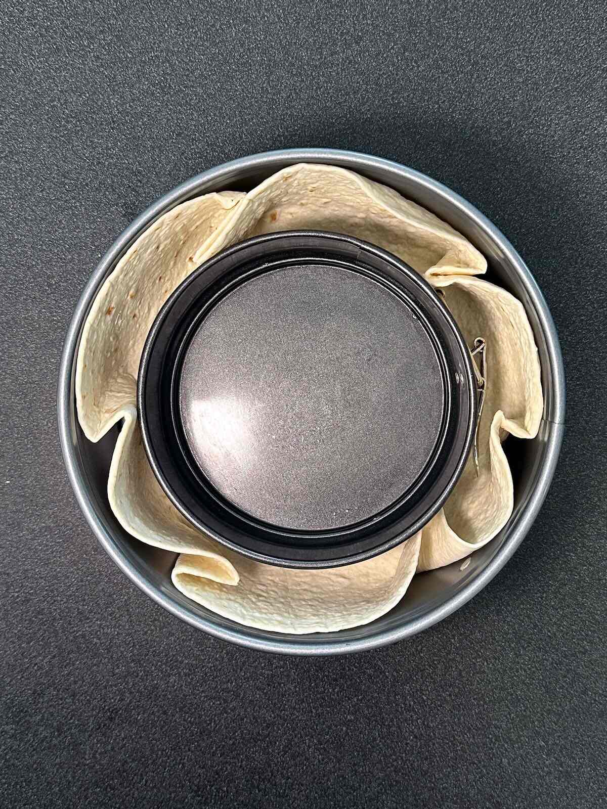 Squishing a tortilla between two oven-safe bowls to make a homemade tortilla bowl. 