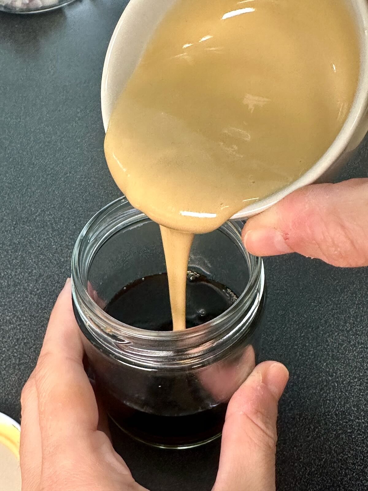 Pouring Oil-Free Balsamic Dressing ingredients into a glass jar for mixing.