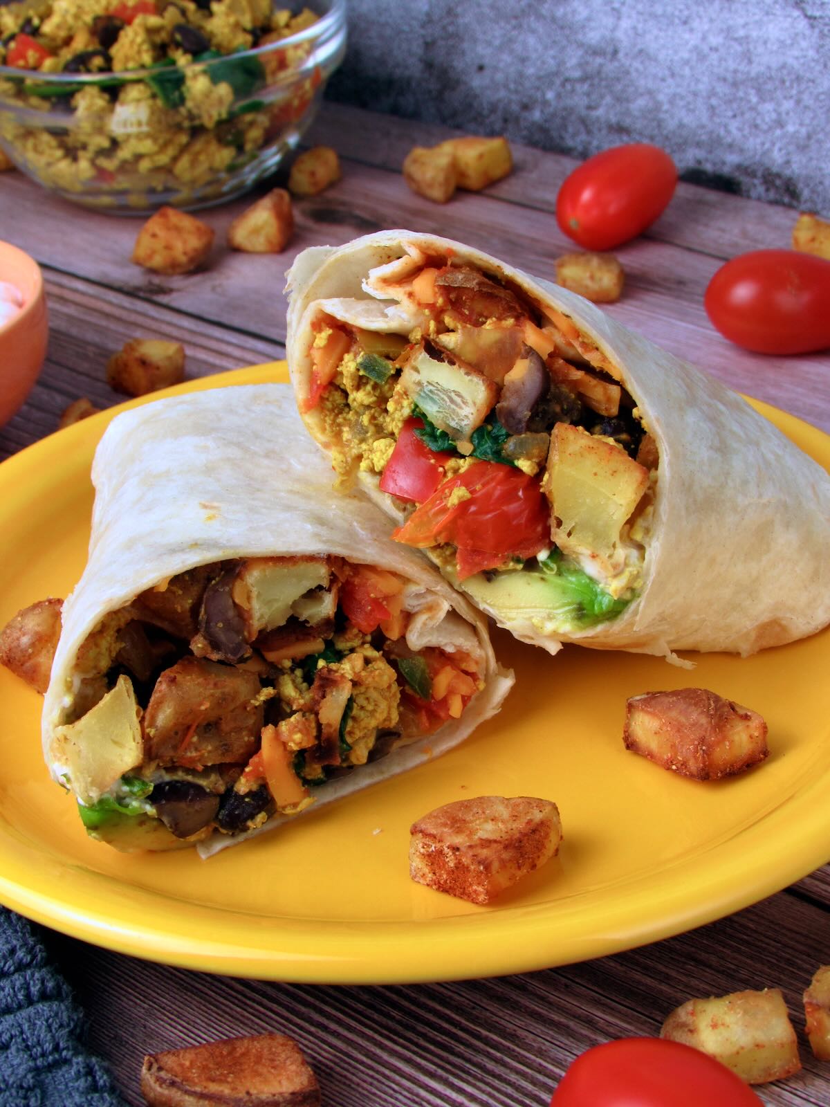 Tex Mex vegan breakfast burritos cut in half, revealing tofu scramble and vegetable filling.