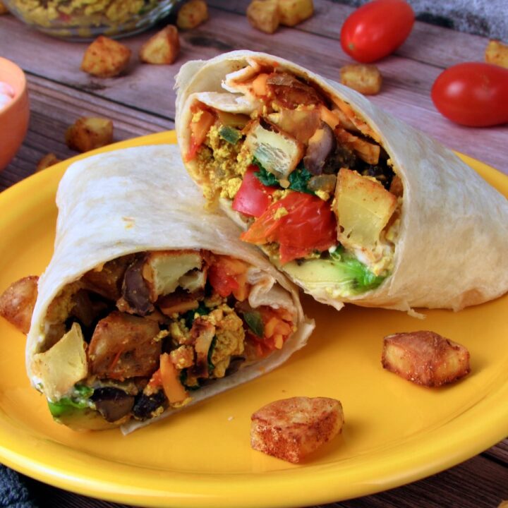 Two halved Tex Mex Vegan Breakfast Burritos with colorful vegetable filling on a yellow plate.