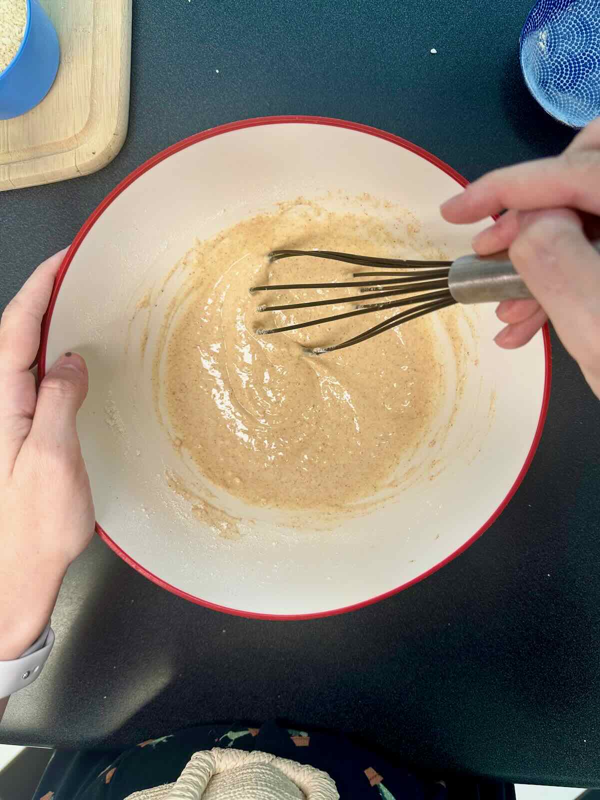Whisking together batter for cauliflower wings in a bowl.