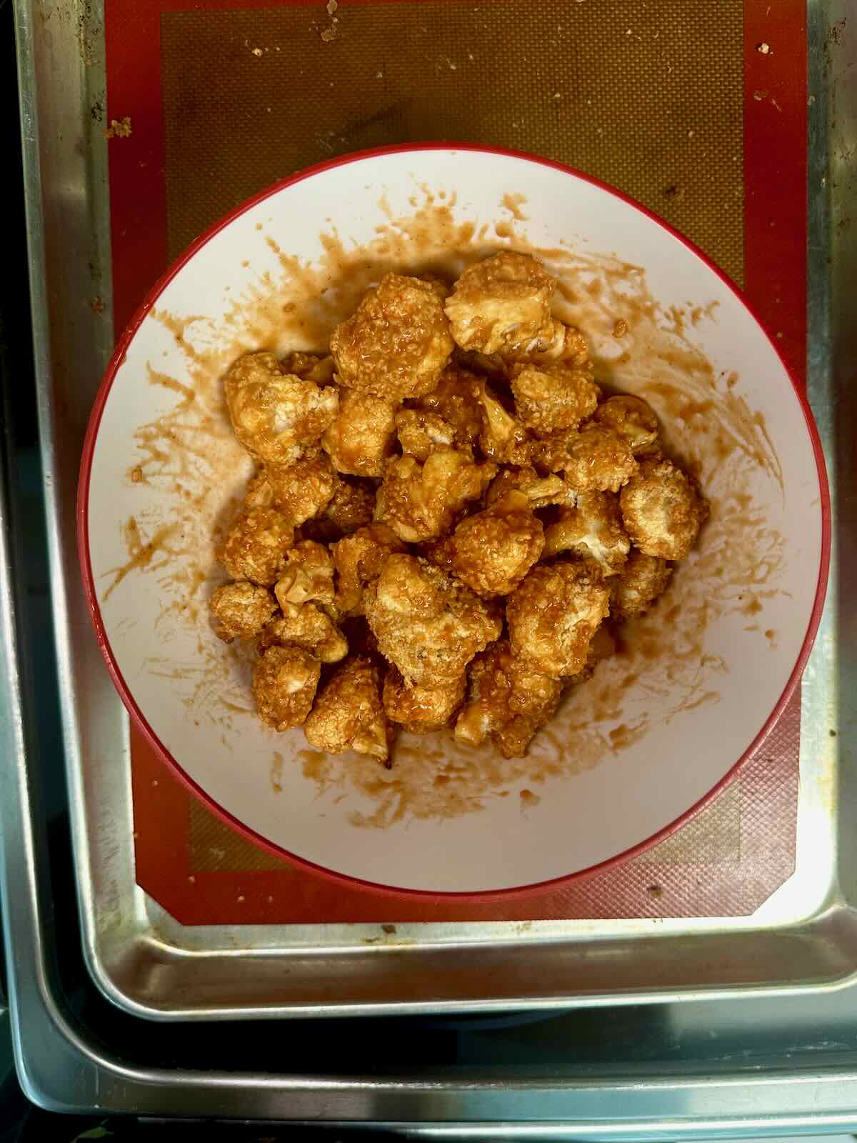 Coating cauliflower bites in homemade buffalo sauce.