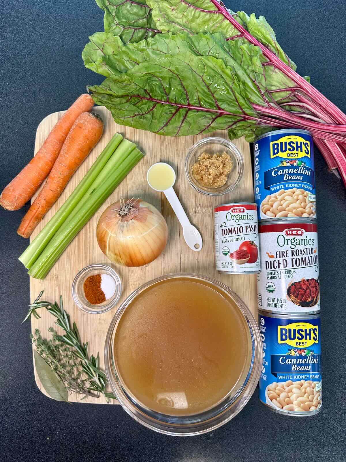 Ingredients for Instant Pot White Bean Soup, including fresh veggies, Swiss chard, aromatic herbs & spices, and veggie broth.