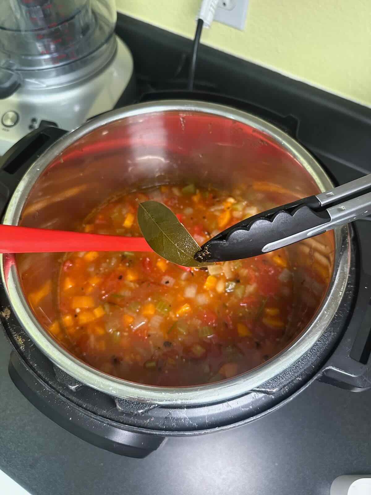 Removing bay leaf from veggie soup.