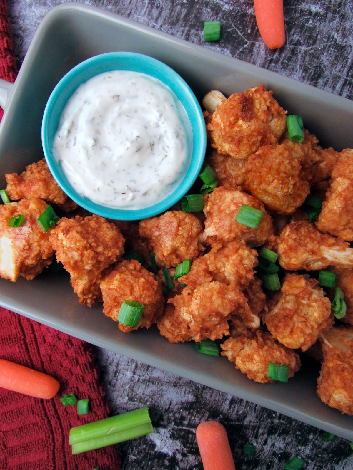 Overhead view of Buffalo Cauliflower Wings, served with vegan ranch as a game day appetizer.