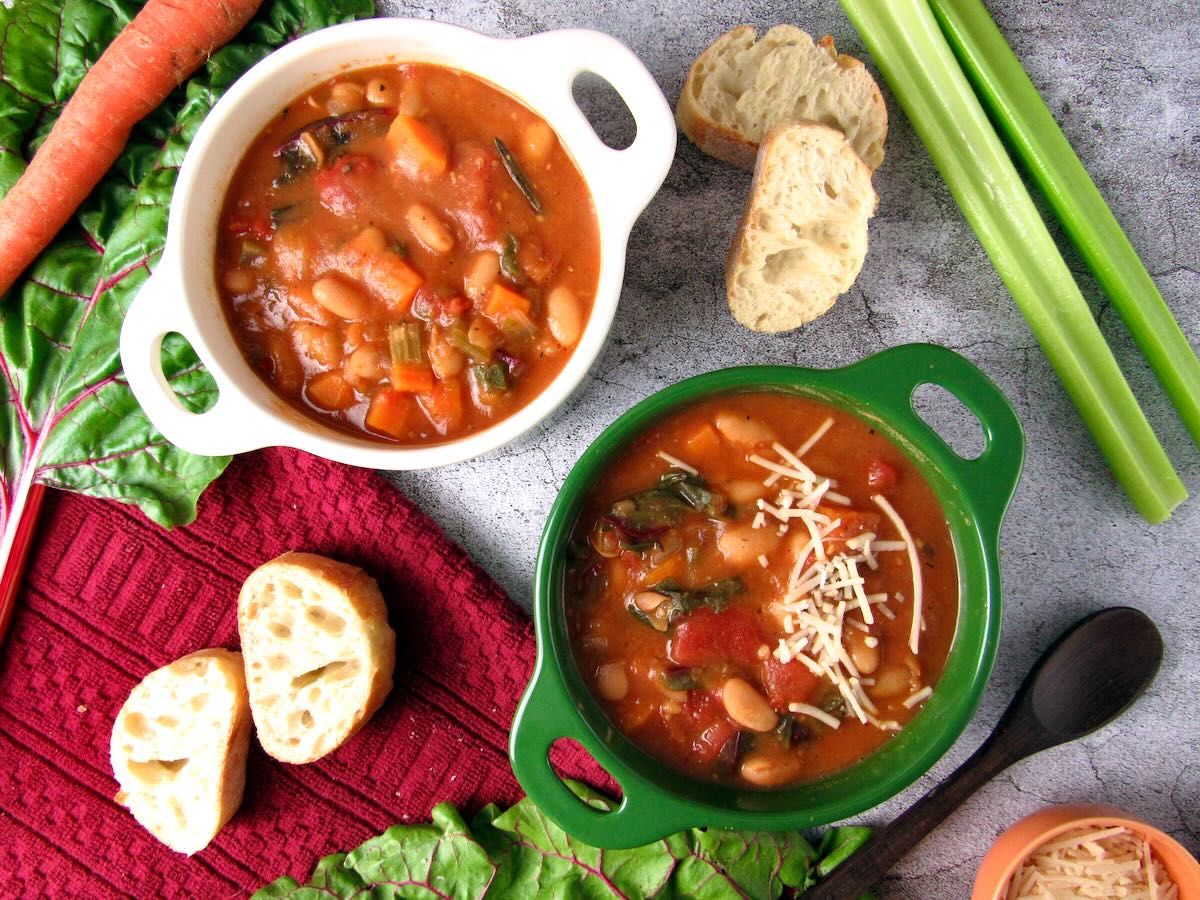 Vegan White Bean Soup, surrounded by celery, carrots, Swiss chard, and baguette.