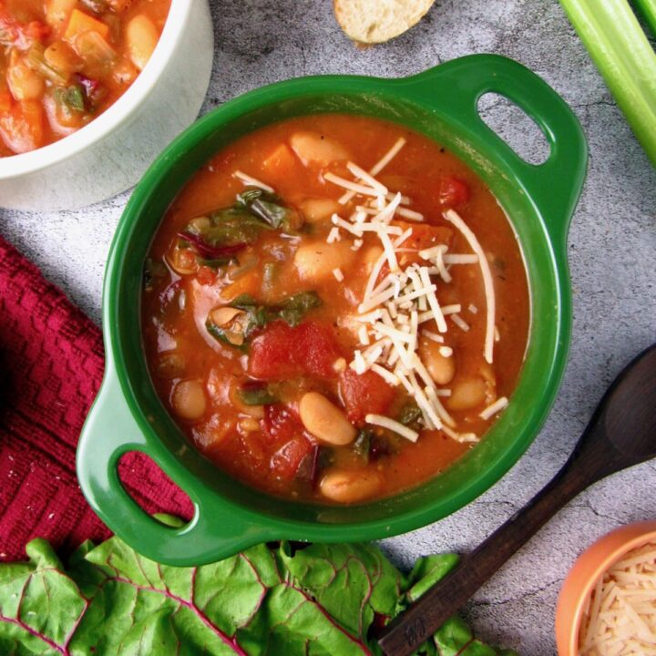 Vegan Instant Pot White Bean Soup with Swiss chard and tomatoes, topped with vegan parmesan.