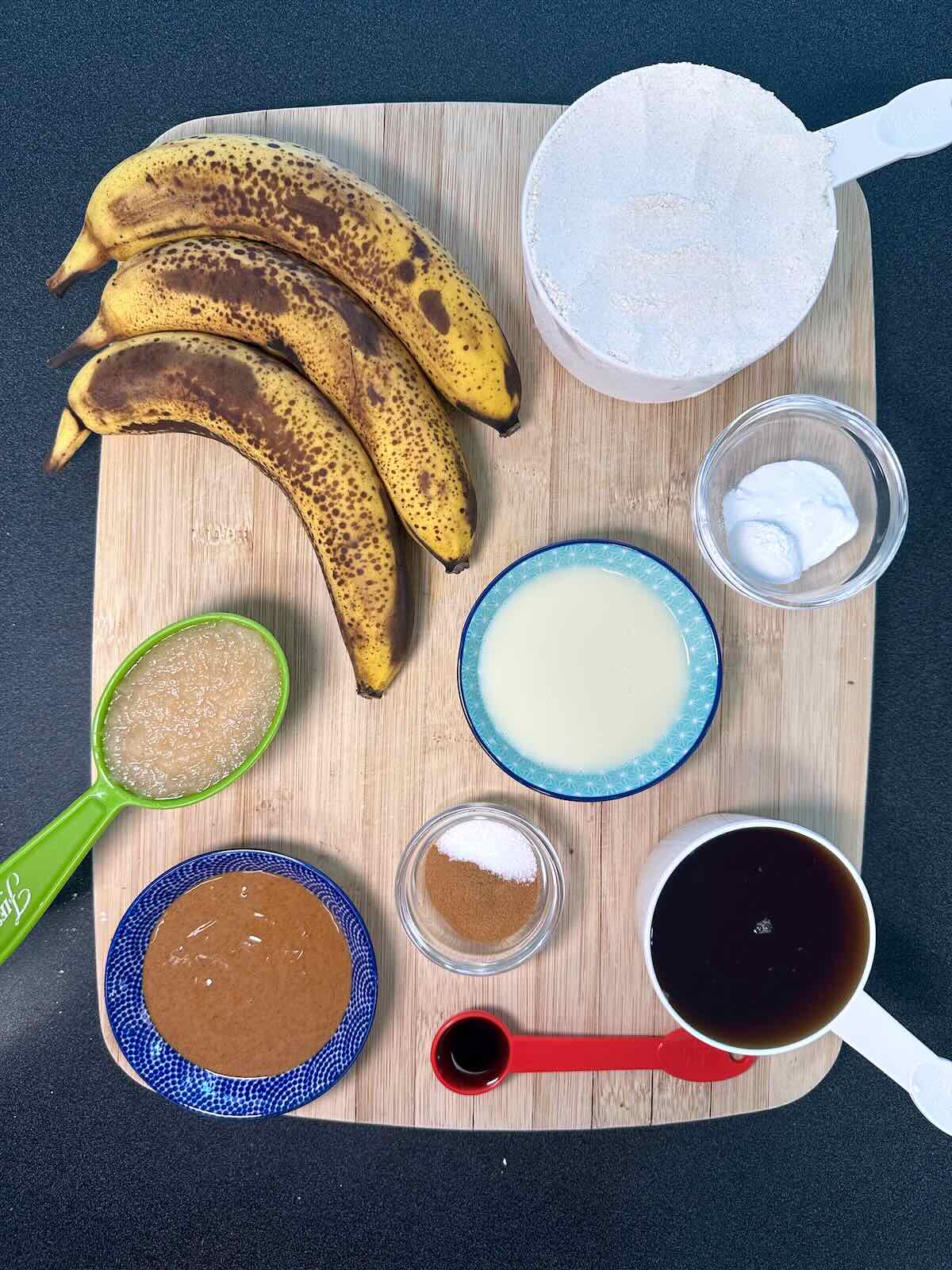 Ingredients for Oil-Free Vegan Banana Bread, including ripe bananas, applesauce, whole wheat pastry flour, pure maple syrup, and spices.