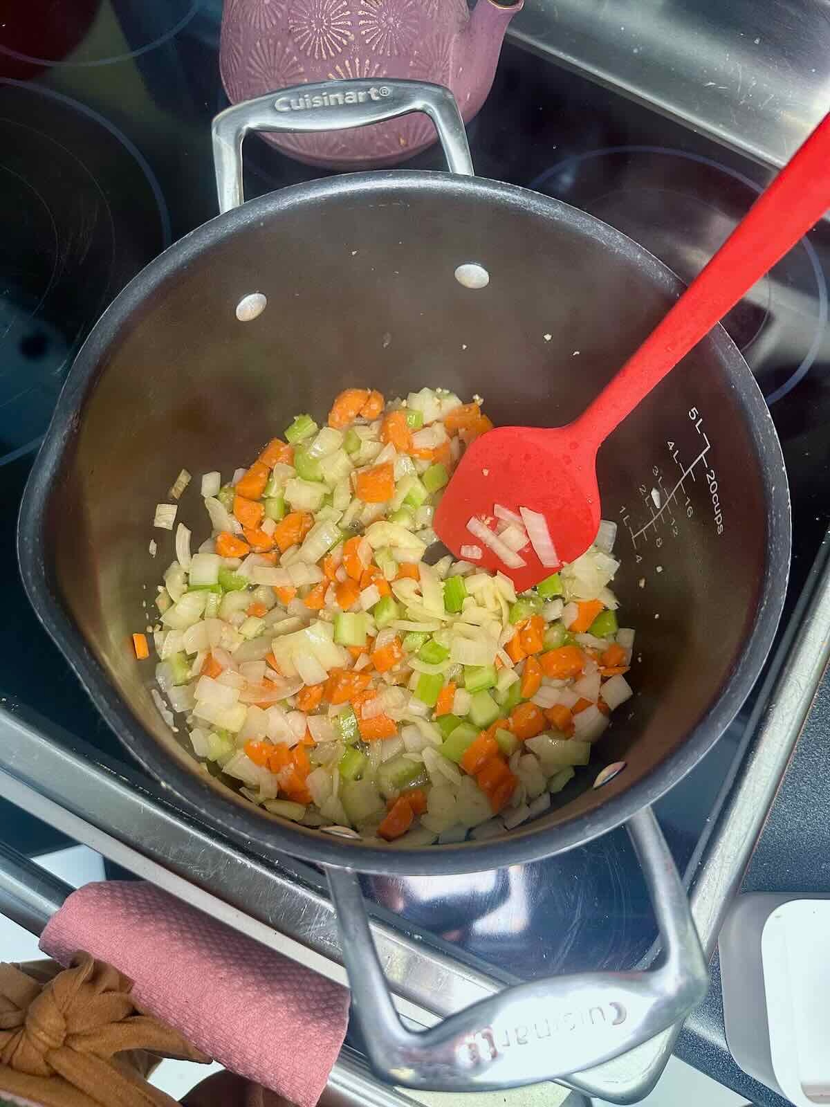 Sautéing onions, carrots, and celery for a vegan soup recipe.