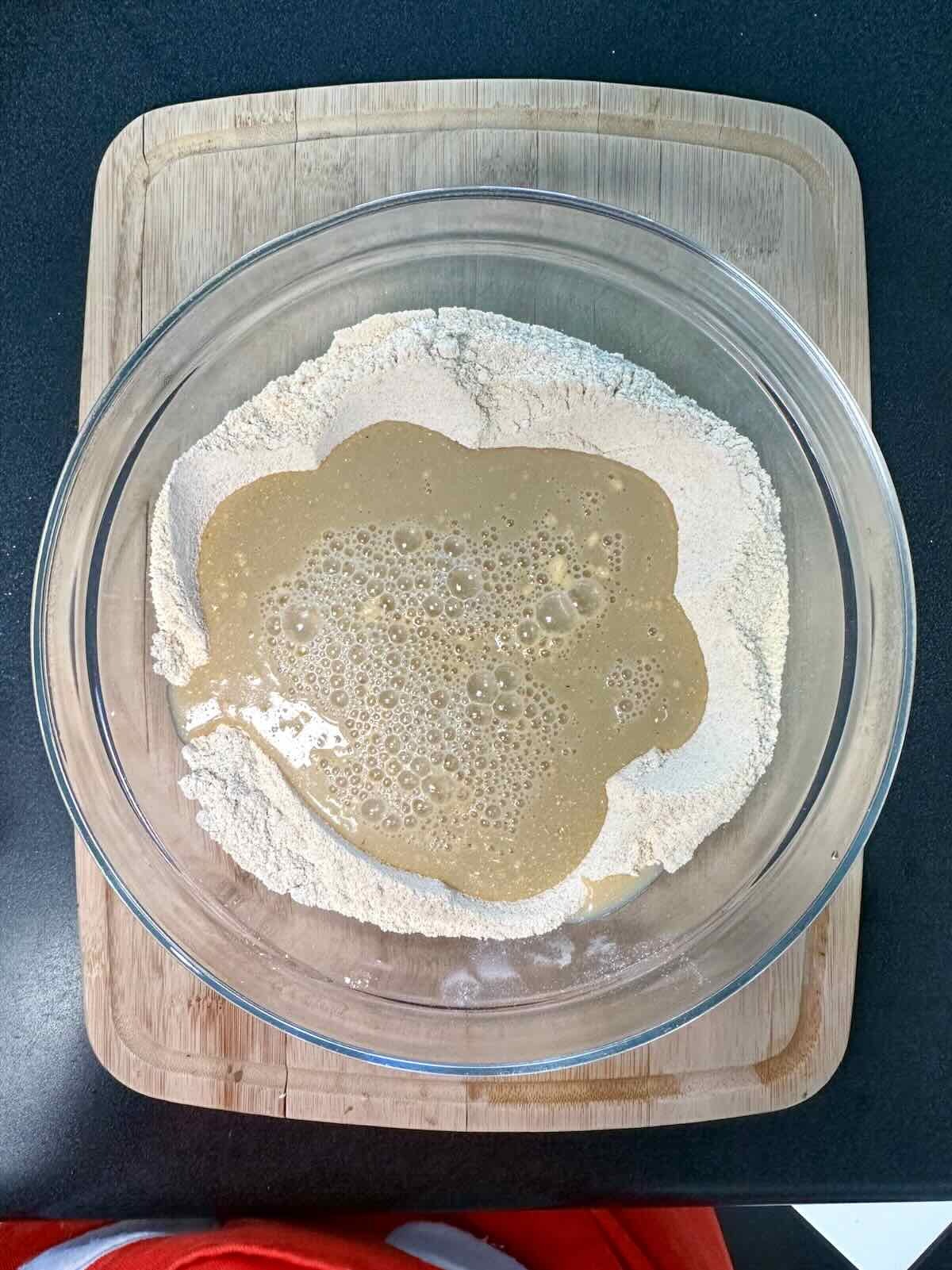 Wet vegan cornbread mixture poured into a well created in the dry ingredients.