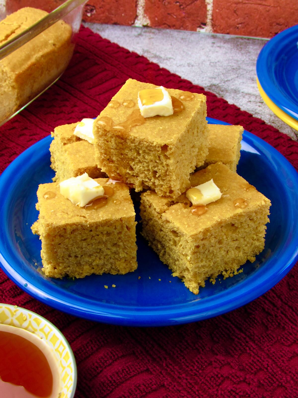 Easy vegan cornbread cut into sweet, fluffy squares with vegan butter and maple syrup on top.
