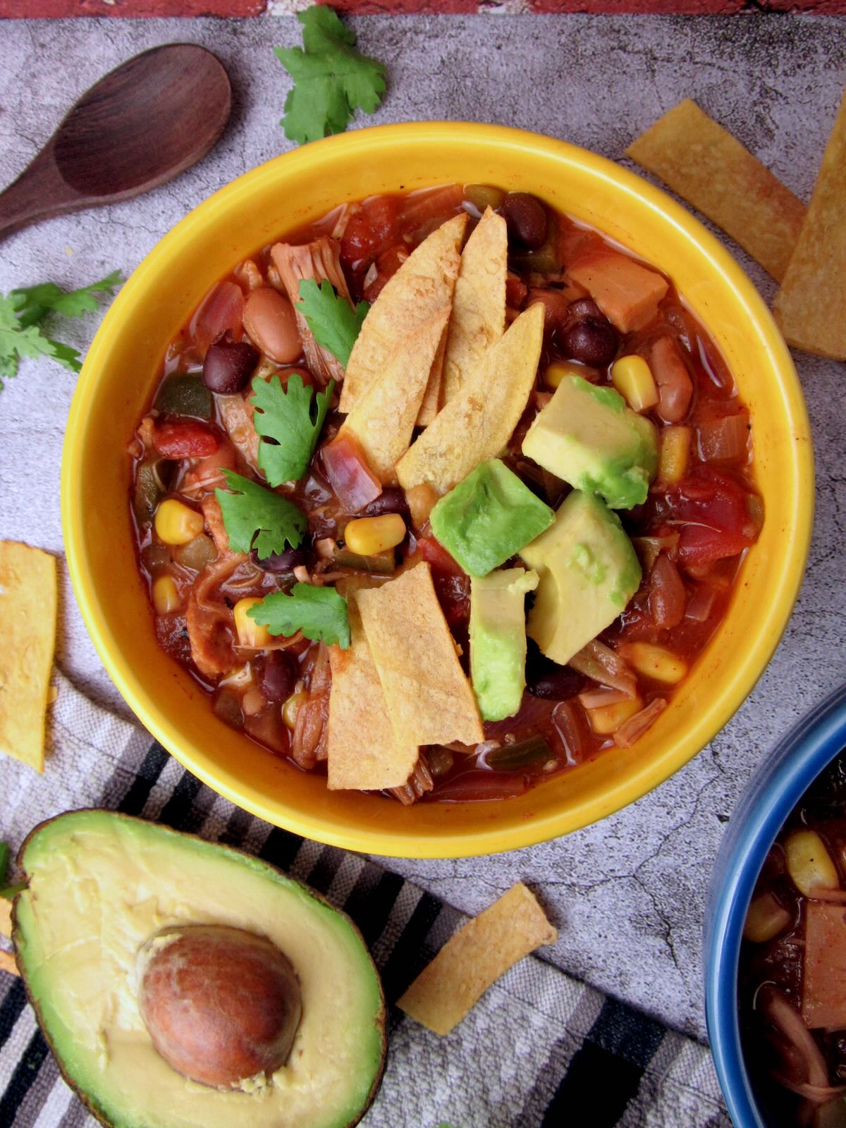 Vegan tortilla soup topped with avocado, cilantro, and tortilla strips.