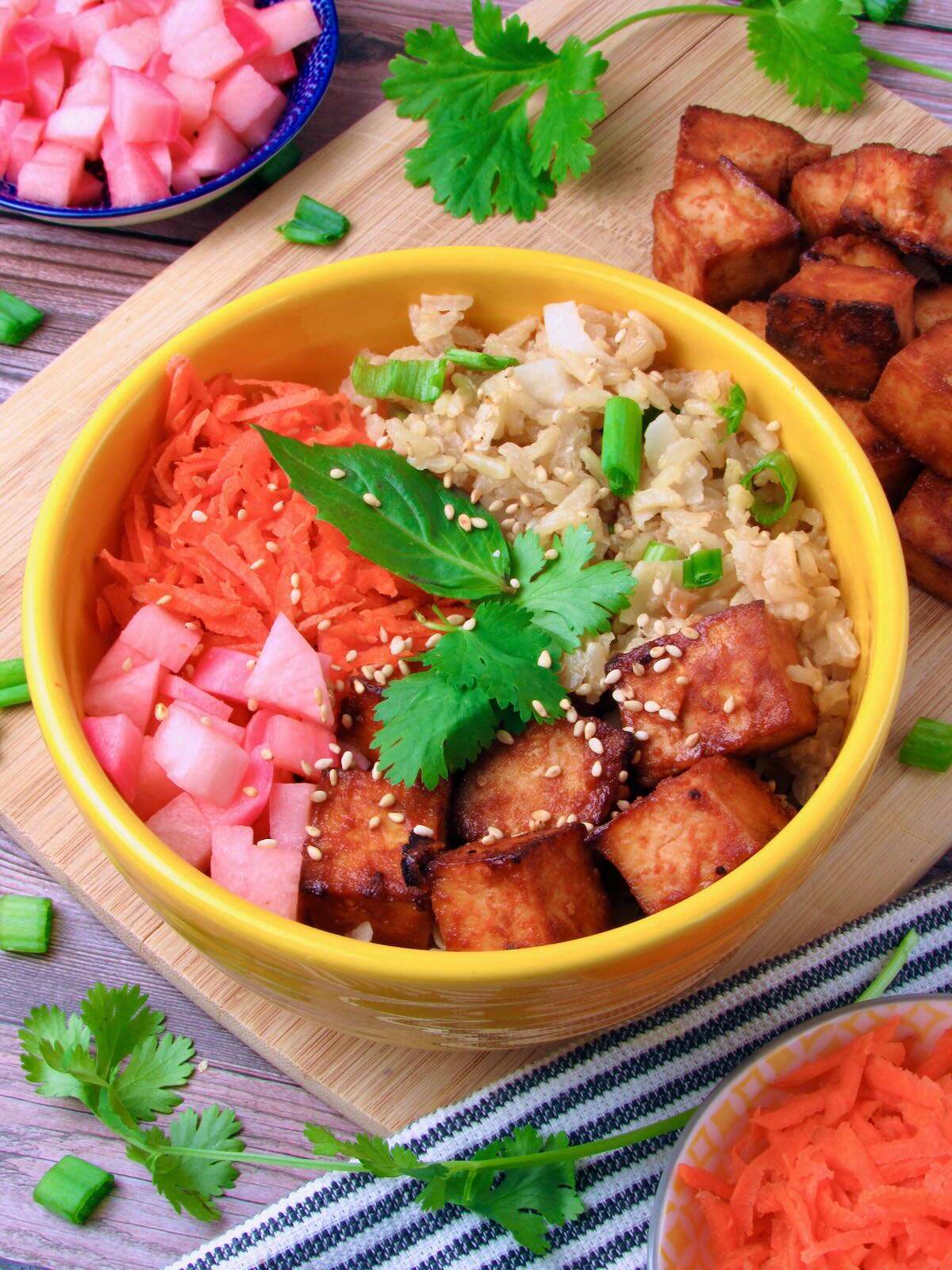 Vegan Buddha Bowl with coconut rice, crispy tofu, pickled vegetables, and fresh herbs.
