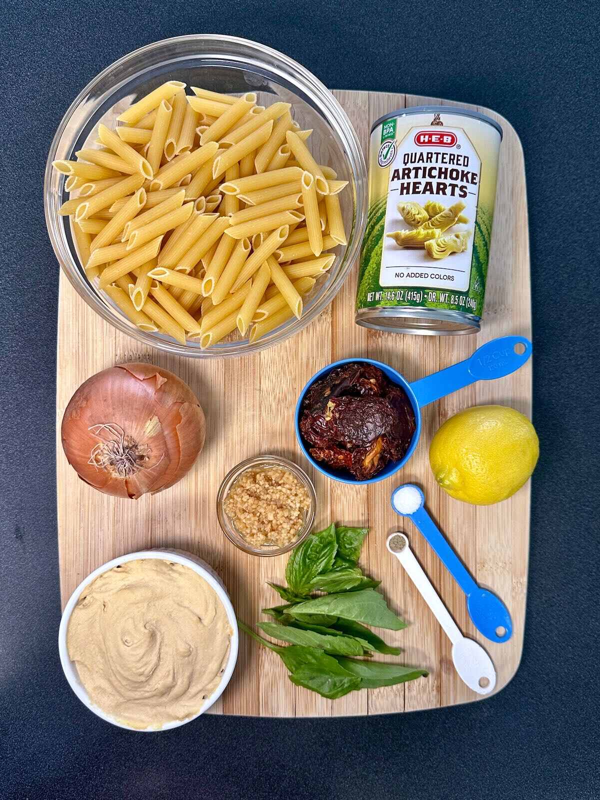 Ingredients for Vegan Hummus Pasta, including homemade hummus, onion, artichoke hearts, and sun-dried tomatoes.