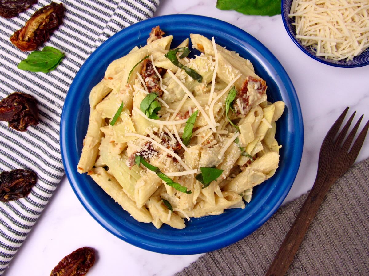 Overhead view of creamy lemon hummus pasta with artichokes and sun-dried tomatoes.