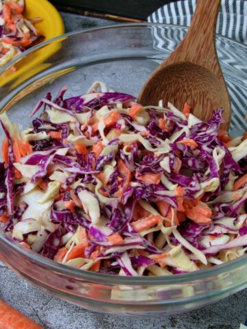 Bowl of creamy vegan coleslaw made with shredded green and red cabbage and carrots.
