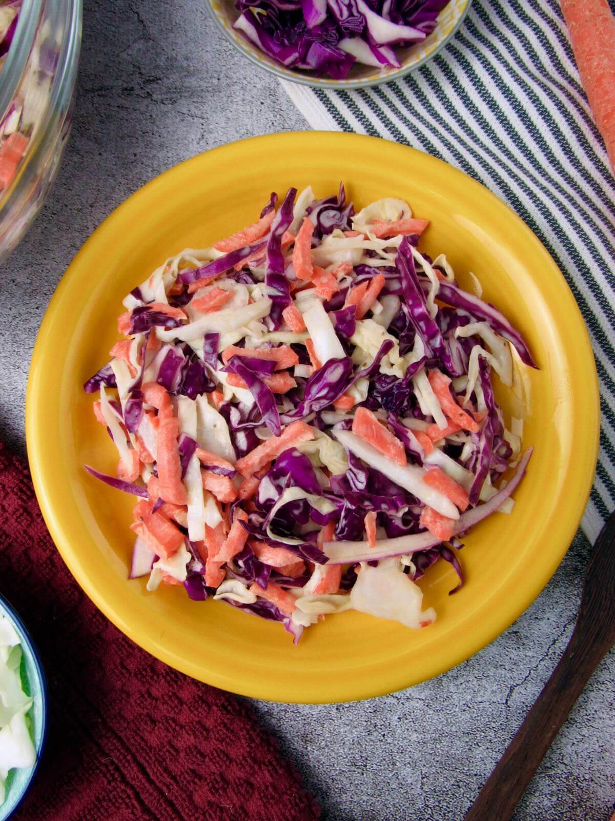 Simple Vegan Coleslaw with crisp veggies on a yellow plate.