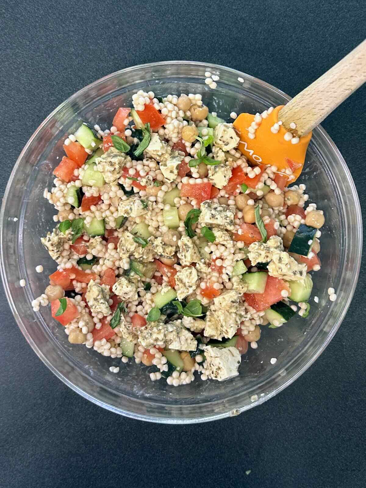 Freshly made Israeli Couscous Salad, topped with vegan feta and fresh basil.