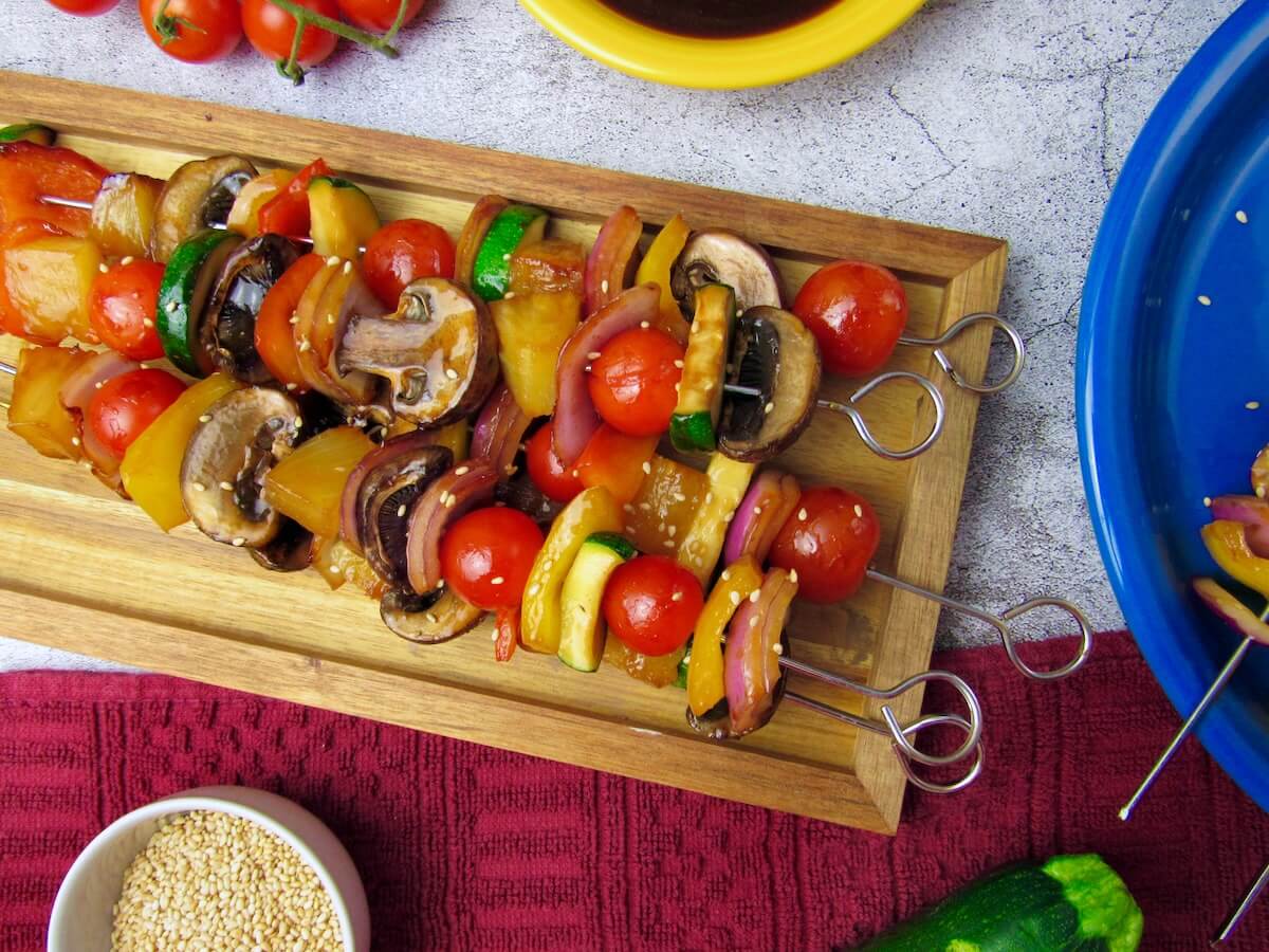 Summer Vegetable Kebabs on a serving tray, with fresh veggies and teriyaki marinade.
