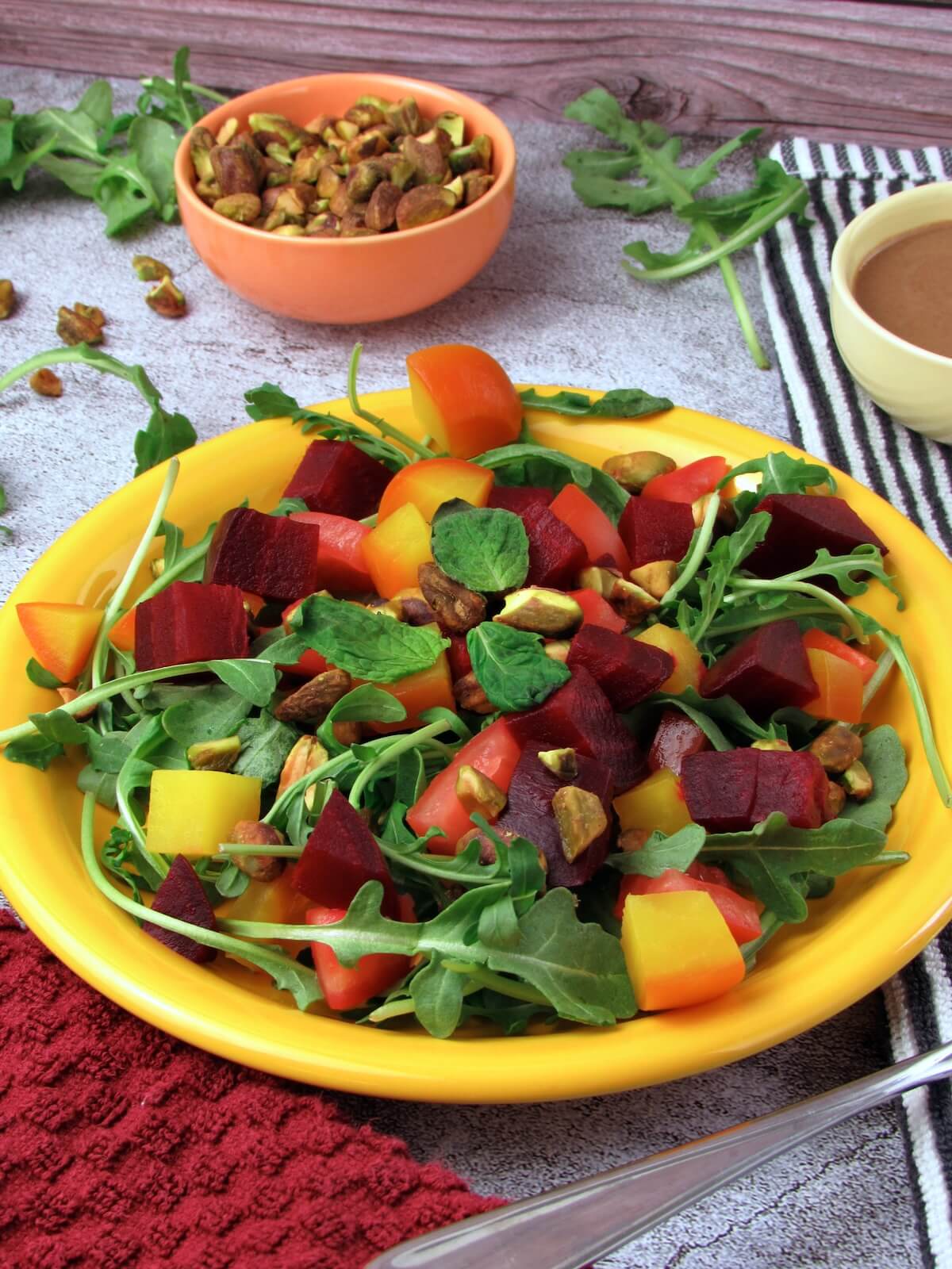 Arugula beet salad with red and golden roasted beets, tomatoes, pistachios, and fresh mint.