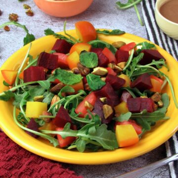 Close up of roasted beet salad with arugula, heirloom tomato, and citrus tahini dressing.