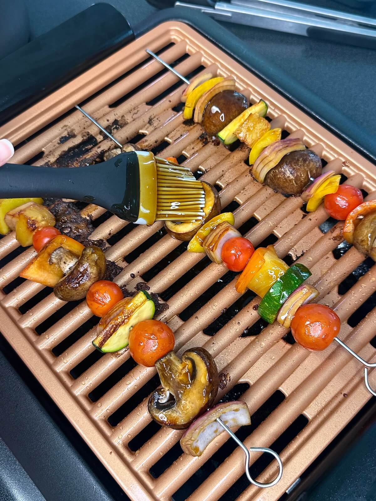 Brushing teriyaki glaze onto summer vegetable skewers.