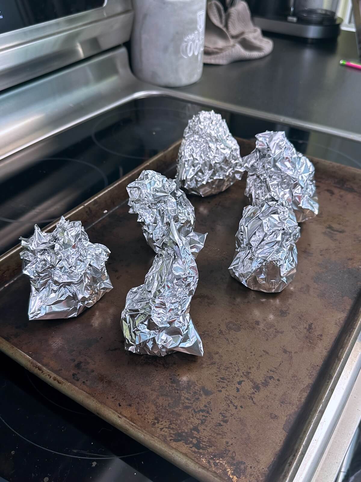 Beets trimmed and loosely wrapped in foil on a baking tray, ready to roast.
