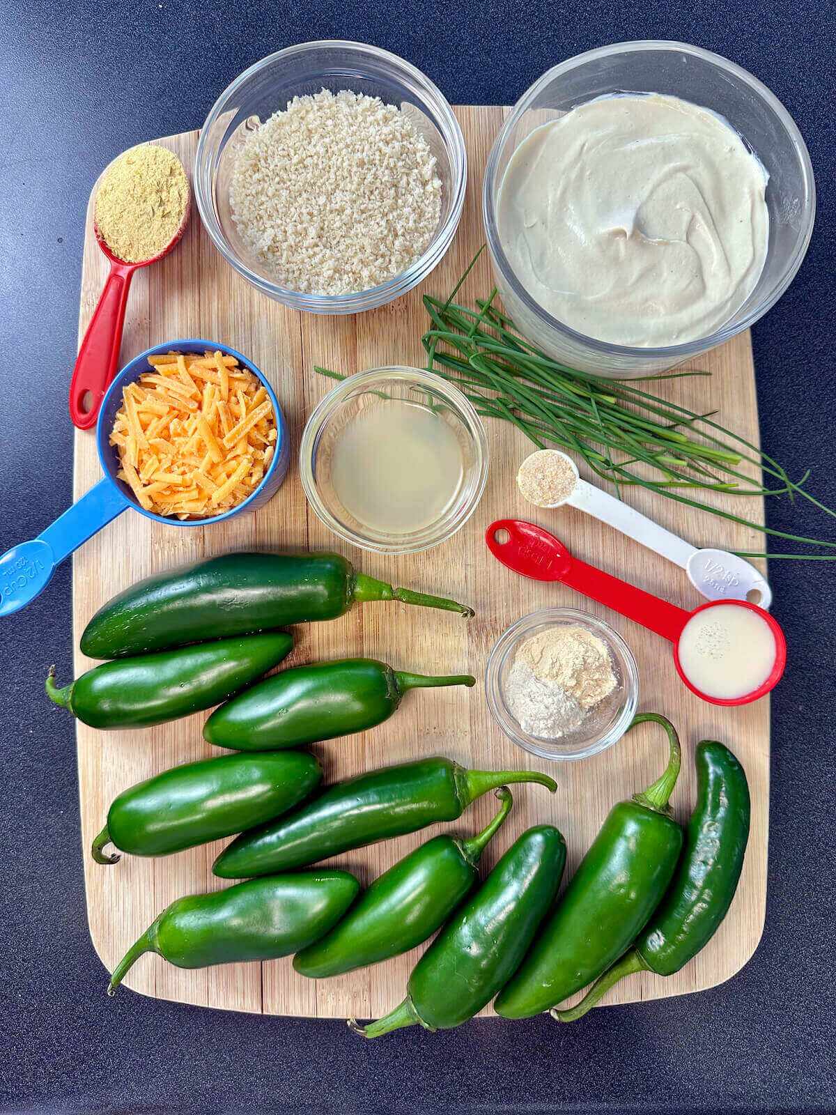 Overhead view of ingredients for dairy-free jalapeño poppers, including vegan cheddar, vegan cream cheese, and fresh chives.