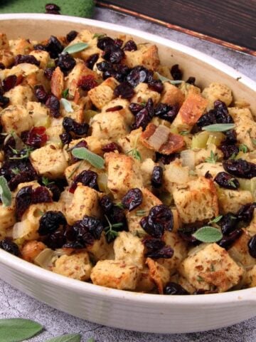 Vegan sourdough Thanksgiving stuffing with fresh herbs and dried cranberries, served in a casserole dish.